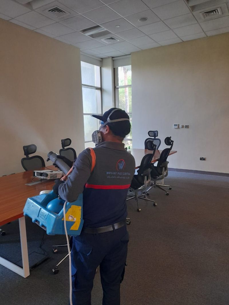 Wipeout Pest Control technician using backpack ULV fogging equipment in a commercial office in the UAE