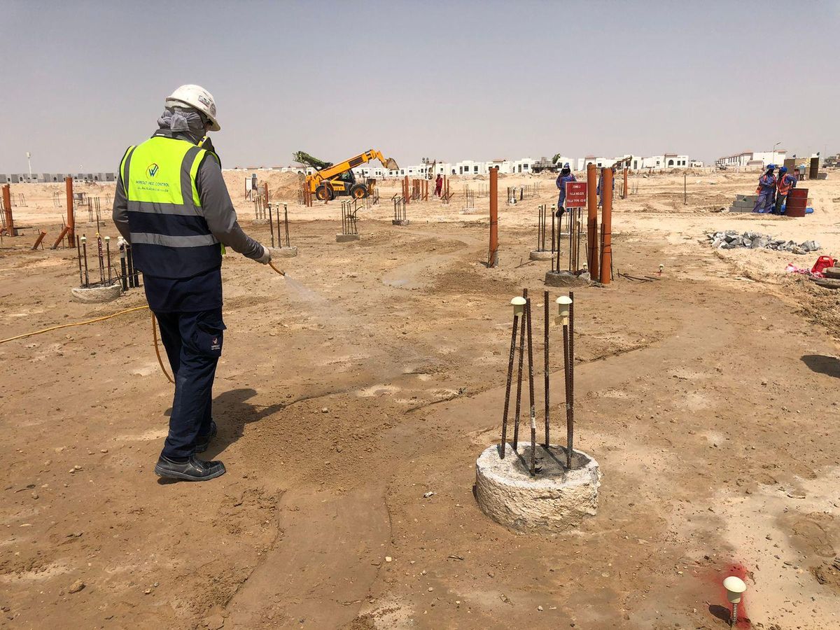 Wipeout Pest Control technician spraying anti-termite soil treatment around foundation columns at a UAE construction site